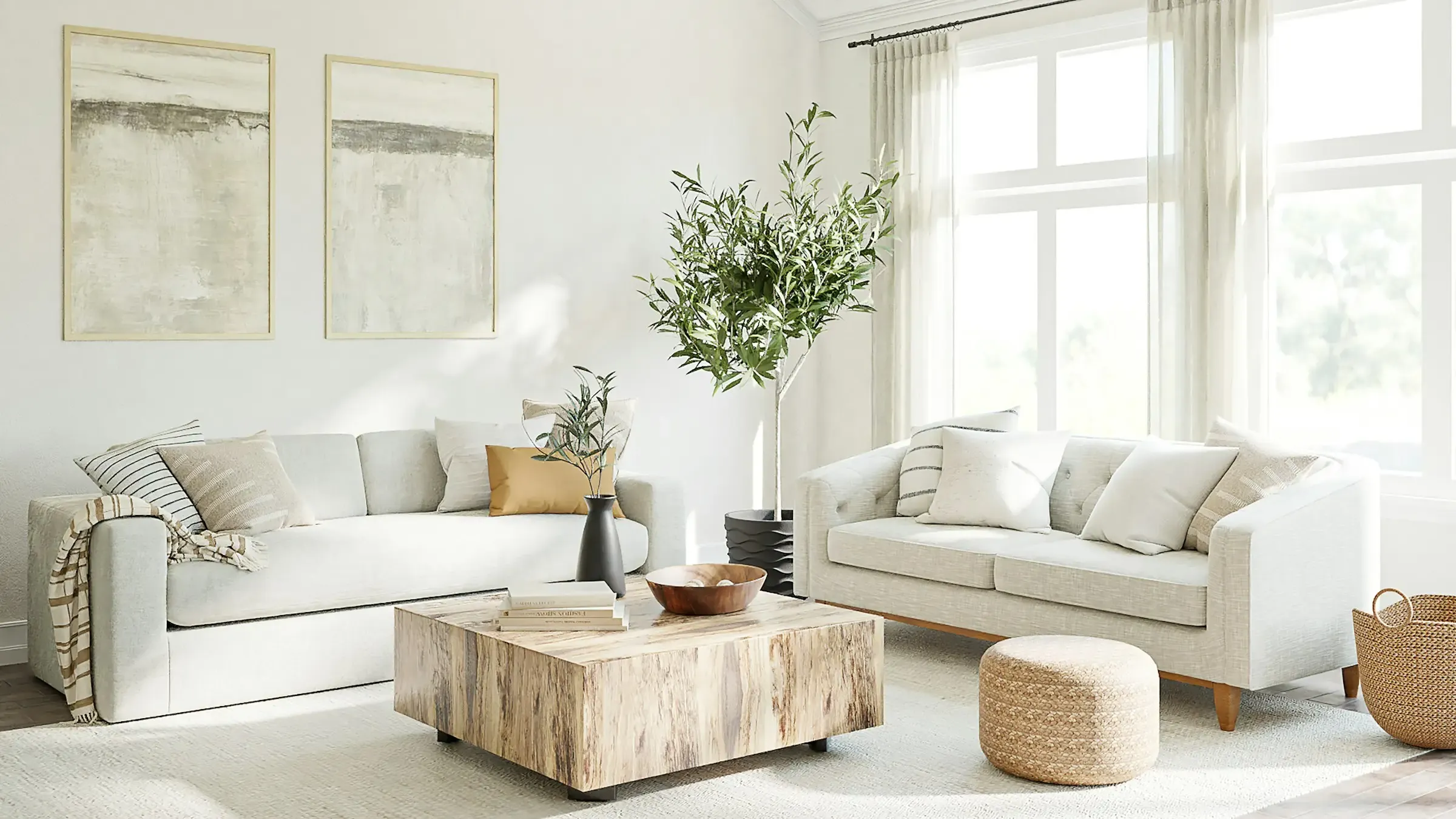 A bright living room with cream sofas, an olive tree and tall windows
