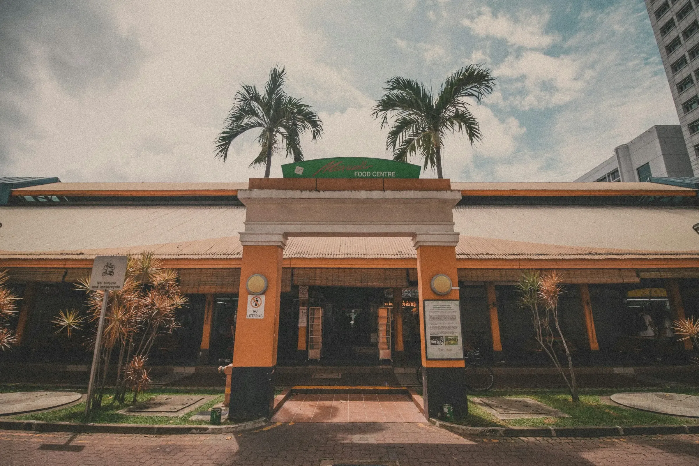 A food centre building with palm trees in front